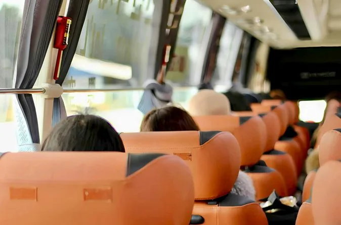 Rows of orange coach seats with passengers seen from behind