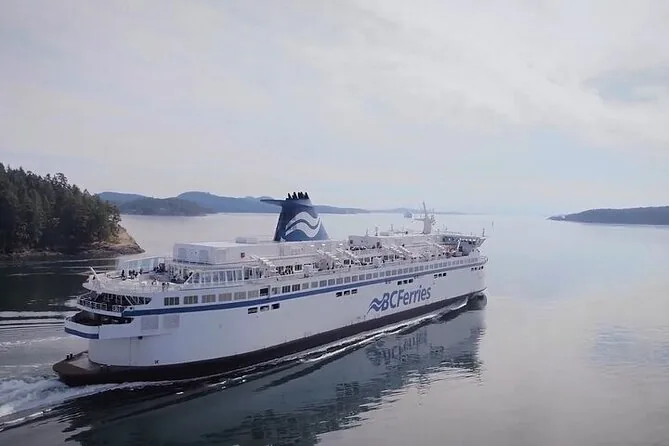 A large white BC Ferries ship crossing calm water past wooded islands
